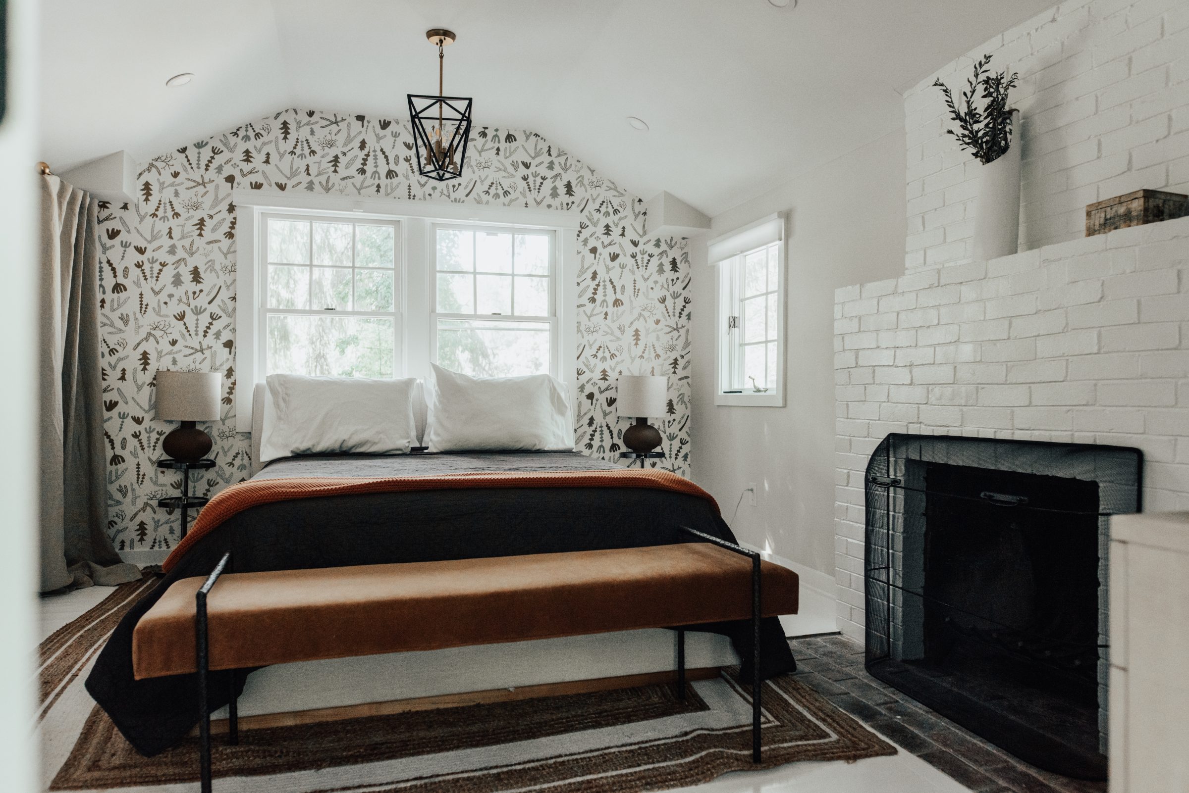 King bedroom with fireplace and patterned wallpaper