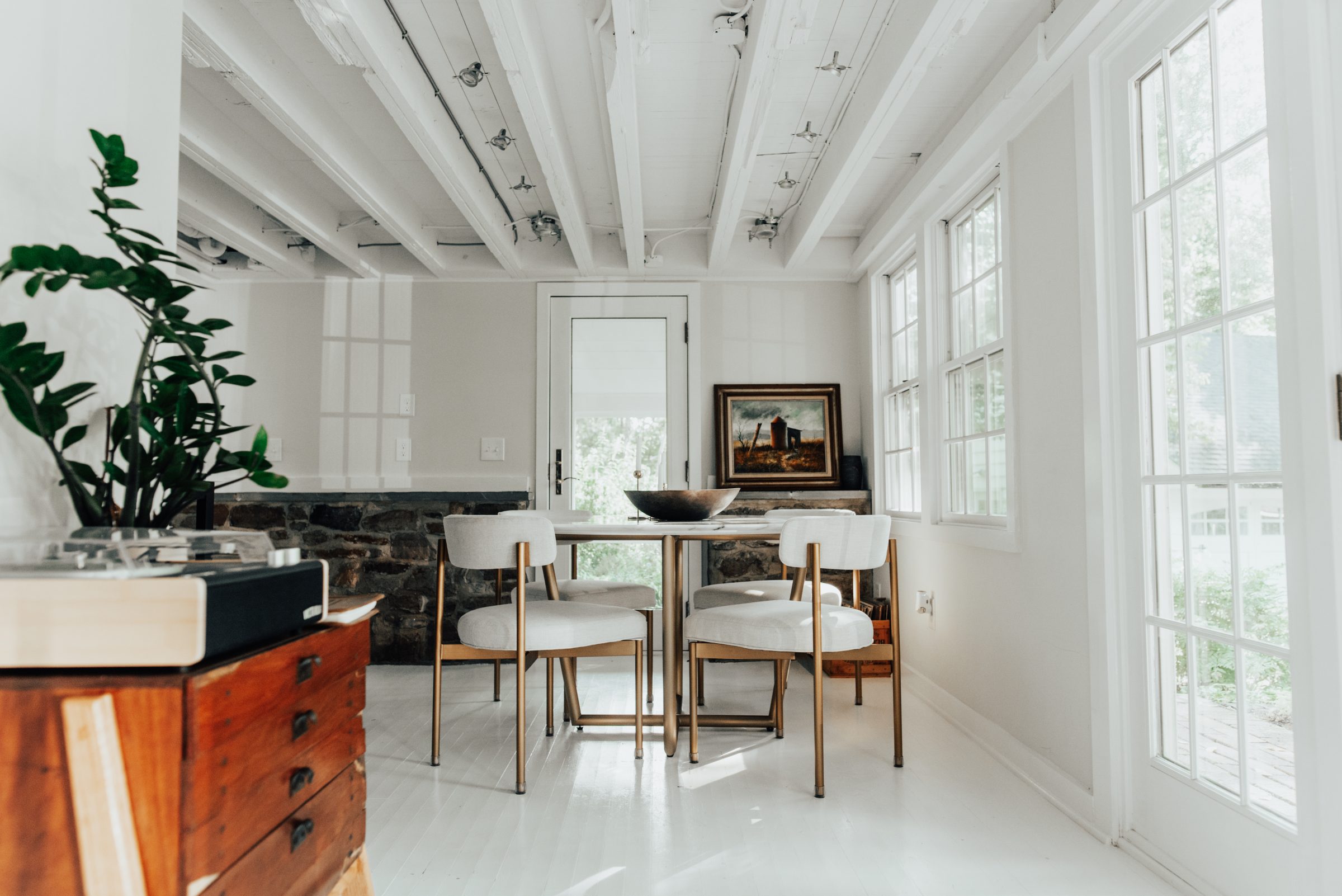 Dining room with marble table, stone knee-wall, and painted beams